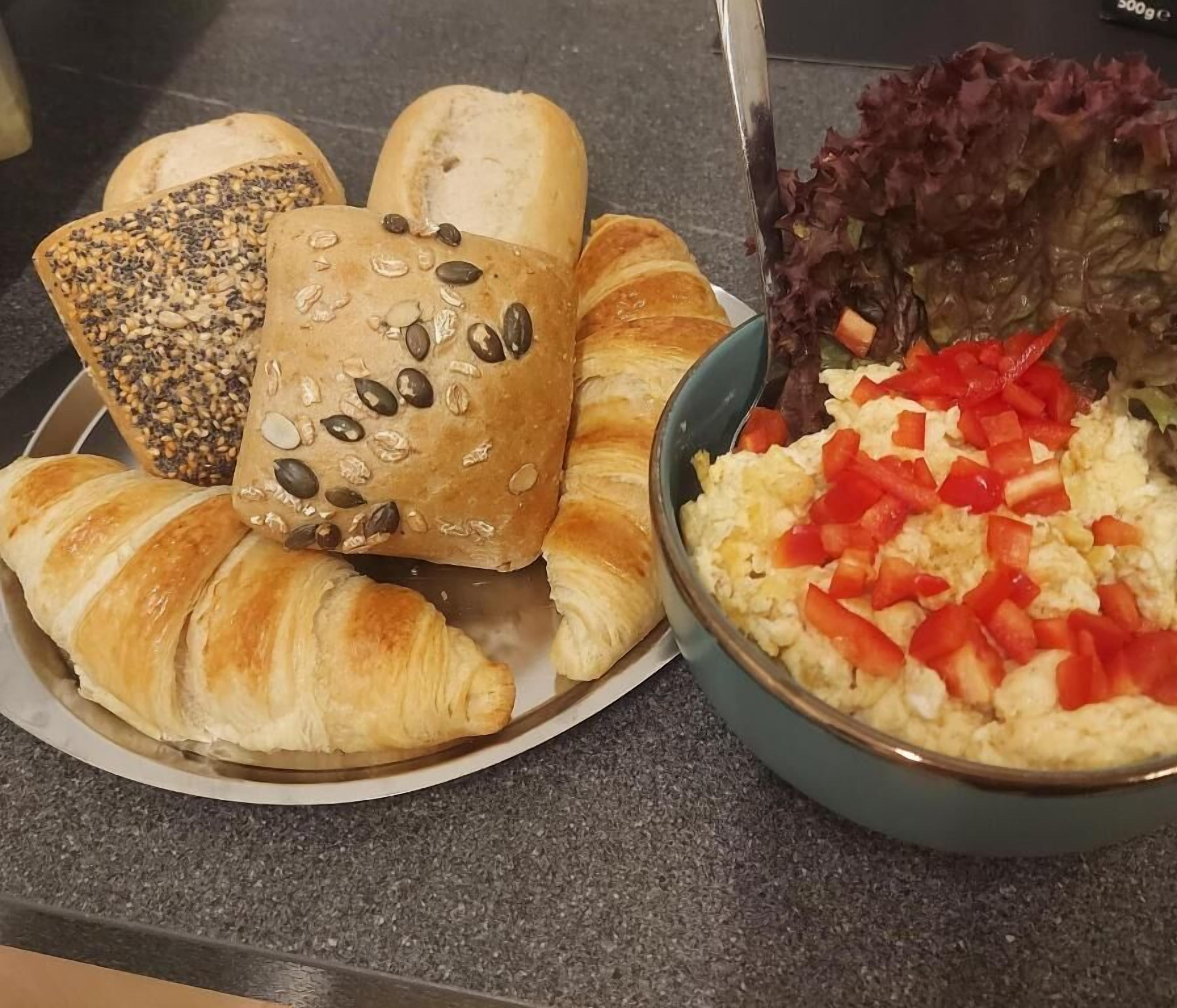 A plate with croissants and a bowl of salad with red peppers.