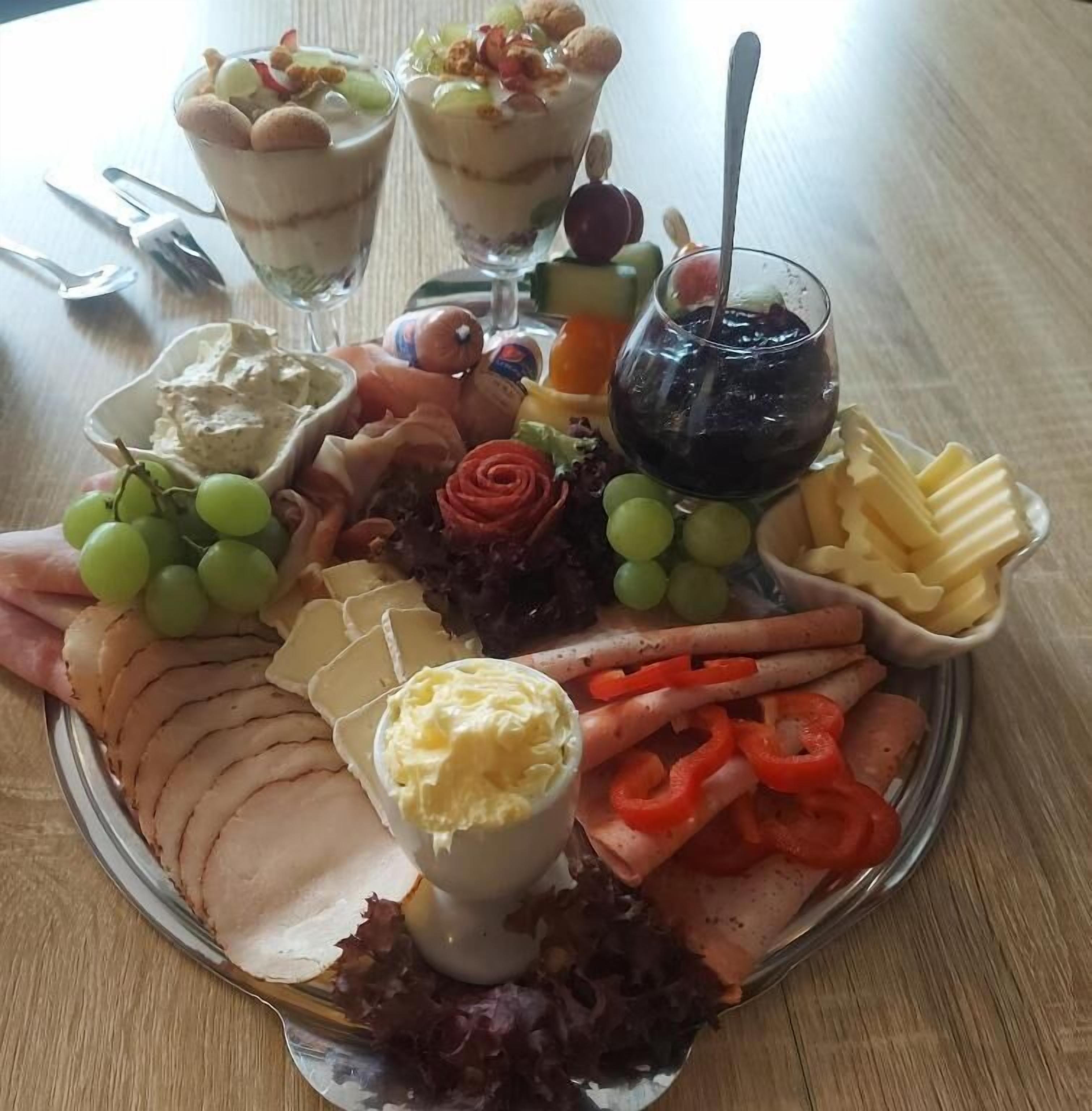 Un grand plat garni de charcuteries, de fromages, de fruits et d’un petit ramequin de beurre.