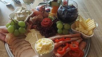A platter with sliced meats, cheeses, fruits, and a small bowl of butter.