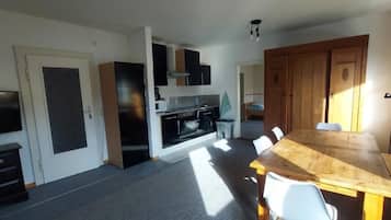 A modern kitchen with a dining area, built-in cabinets, and a large wooden table.