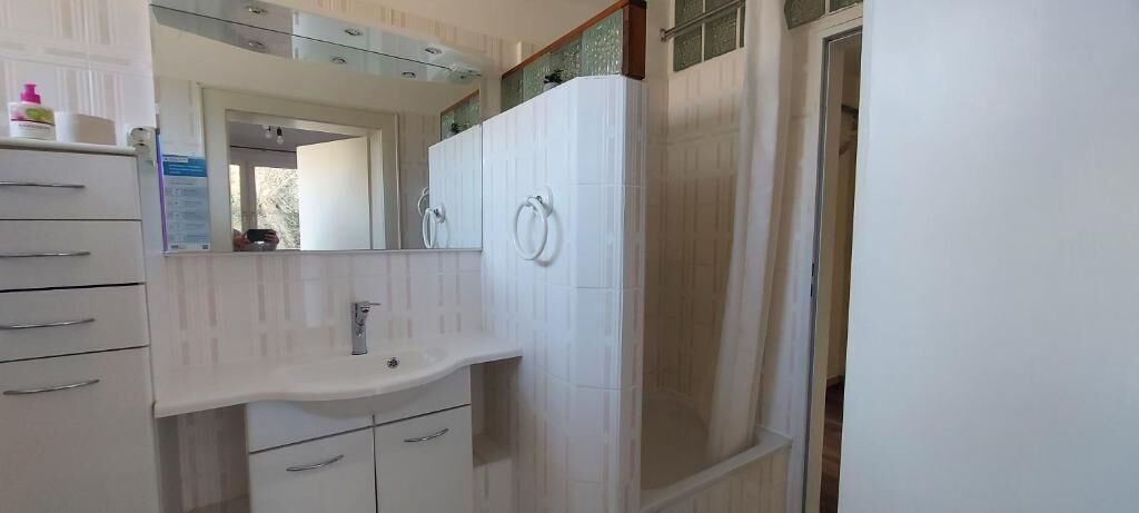 A bathroom with a sink, mirror, and a shower area.