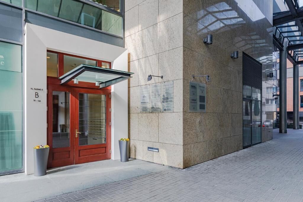 Ein modernes Gebäude mit roter Tür, Glasfenstern und einer Kachelfassade.