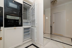 A kitchen with a built-in oven and a refrigerator with multiple shelves. - Bagno 2 Premium Apartment, City Center (Warszawa)