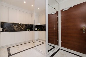 A modern kitchen with white cabinetry, black marble countertops, and a wooden door. - Bagno 2 Premium Apartment, City Center (Warszawa)