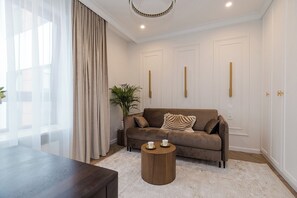 A modern living room with a brown sofa, a round wooden coffee table, and a large window with sheer curtains. - Bagno 2 Premium Apartment, City Center (Warszawa)