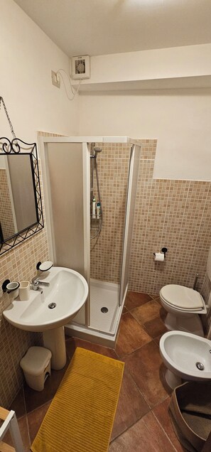 Une salle de bain avec une douche, deux lavabos, des toilettes et un miroir.