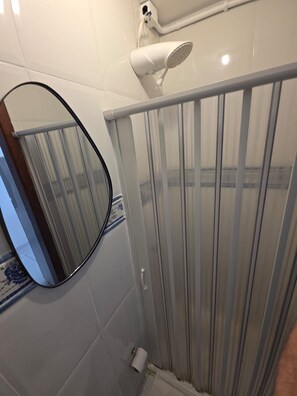 A bathroom with a shower, a toilet, and a mirror. - Studio Pé na Areia em Copacabana (Rio de Janeiro)
