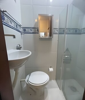Ein Badezimmer mit Toilette, Waschbecken und einer Duschkabine aus Glas.