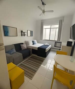Ein modernes Schlafzimmer mit Bett, Sofa, Esstisch und Deckenventilator.
