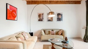 Een woonkamer met twee banken, een glazen salontafel en een vloerlamp.