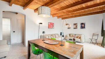Un salon moderne avec un plafond en bois, une table à manger, des chaises vertes et un canapé.