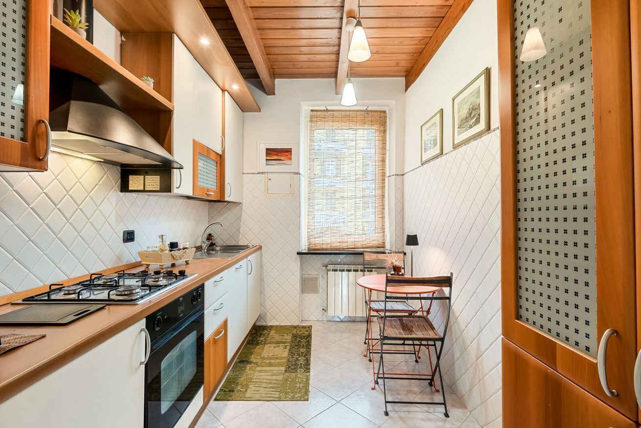 Une cuisine de taille réduite, équipée d’une cuisinière à gaz, d’un four et de meubles de rangement en bois.