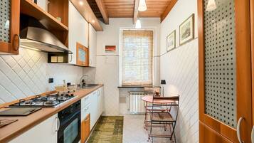 Une cuisine de taille réduite, équipée d’une cuisinière à gaz, d’un four et de meubles de rangement en bois.