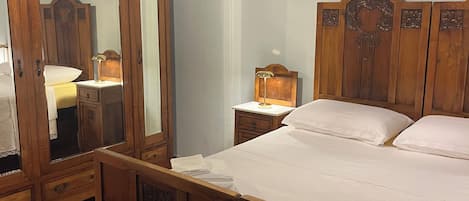 Un dormitorio con una cama de madera, una mesita de noche, un espejo y una araña.