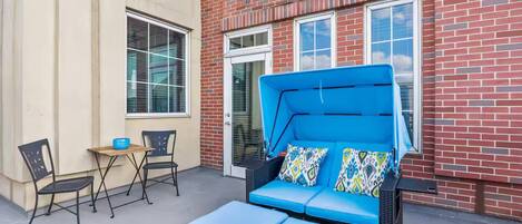 An outdoor seating area with a blue sofa, two chairs, and a small table.