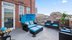 Een terras op het dak met buitenmeubilair, een overdekt zitgedeelte en een uitzicht op de skyline.