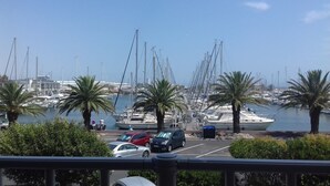 A marina with boats docked, palm trees, and a clear sky. - Le Maryland - Climatisé à 100 m de la plage (Leucate)