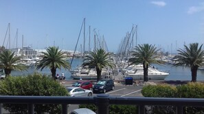 A marina with boats docked, palm trees, and a clear sky. - Le Maryland - Climatisé à 100 m de la plage (Leucate)