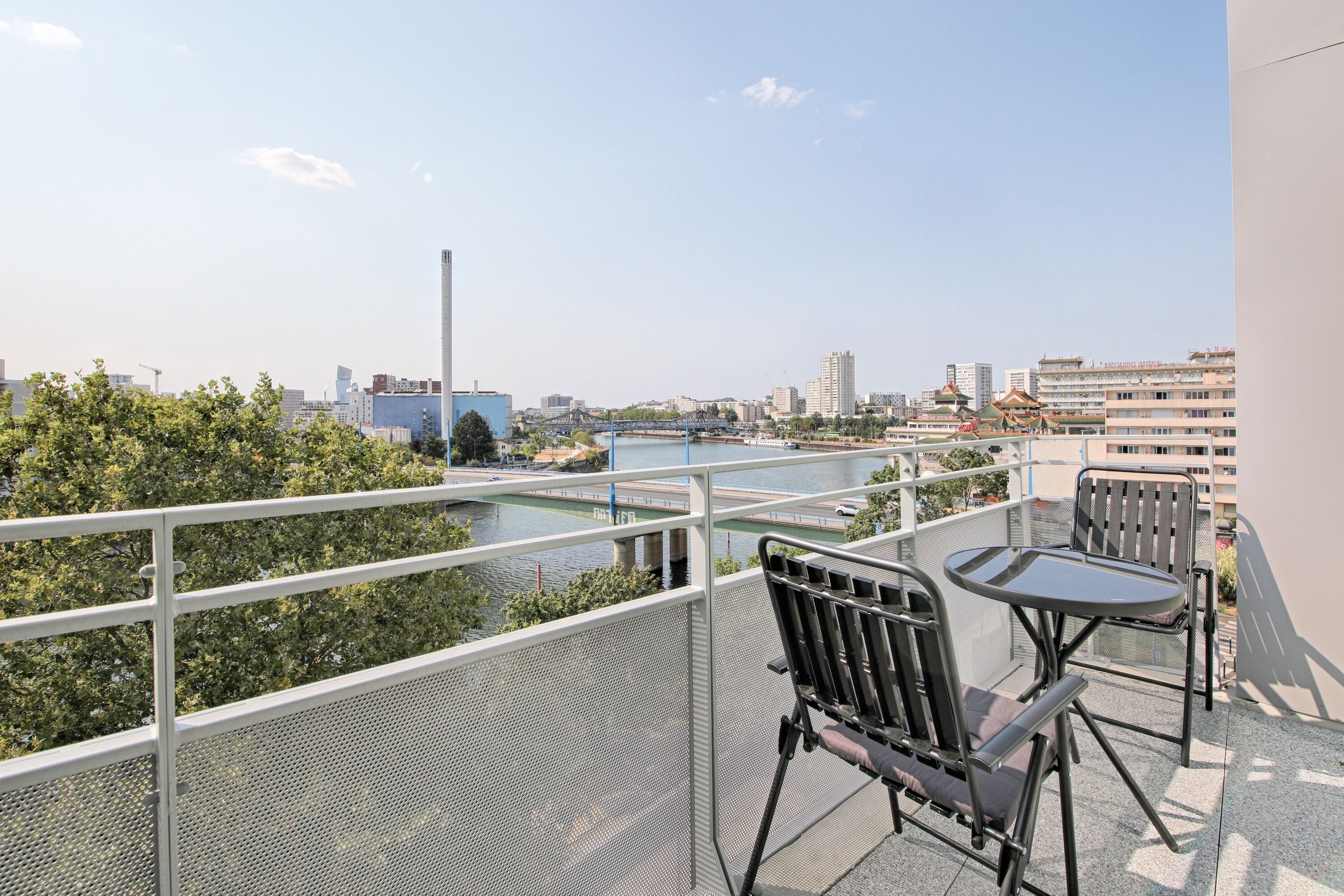 A balcony with a view of a river, a bridge, and city buildings.