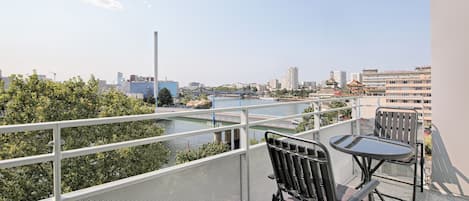 A balcony with a view of a river, a bridge, and city buildings.