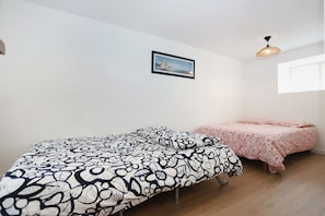A bedroom with two beds, one with a black and white floral bedspread and the other with a pink paisley bedspread. There is a framed picture on the wall and a hanging light fixture. - Studio Émeraude - L’élégance d’une escale bretonne (Dol-de-Bretagne)