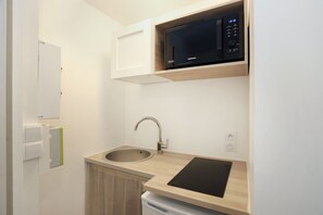 A compact kitchen with a microwave, sink, and a dishwasher. - Studio Granit - L’élégance d’une escale bretonne (Dol-de-Bretagne)