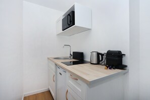 Eine kleine Küchenzeile mit Spüle, Toaster, Wasserkocher und Kaffeemaschine.