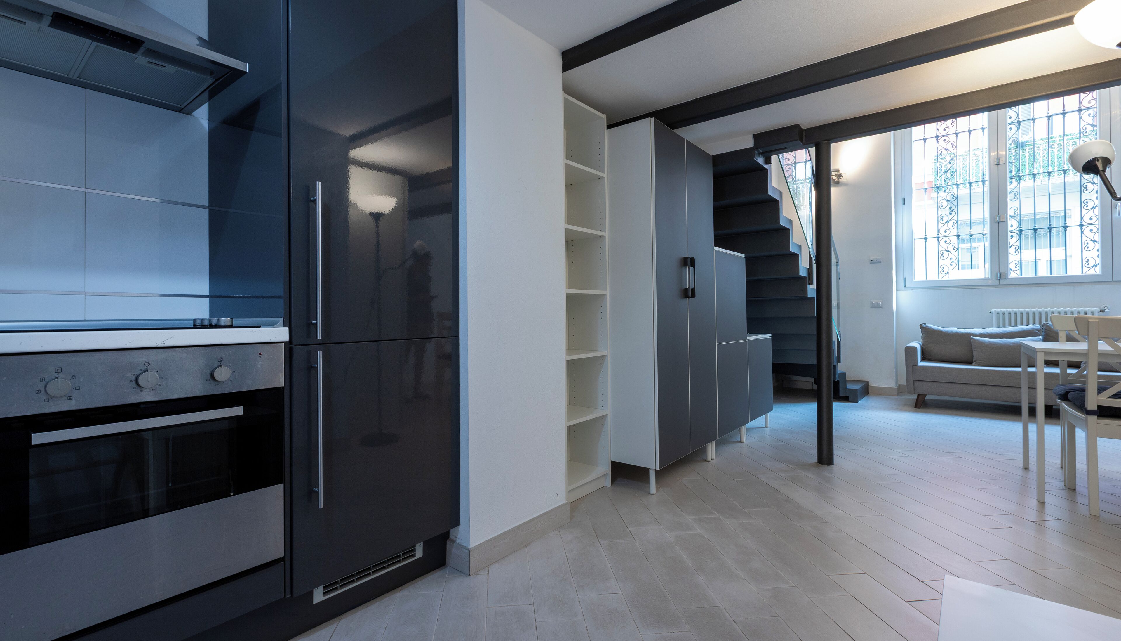Eine moderne Küche mit integrierten Geräten, einer Treppe zu einem Balkon und einem Essbereich mit Tisch und Stühlen.