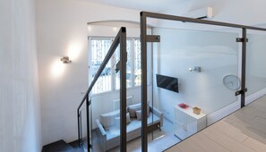 A modern interior with a staircase, a sofa, a TV, and a clock. - Italianway Easy - Verro 46 (Milan)