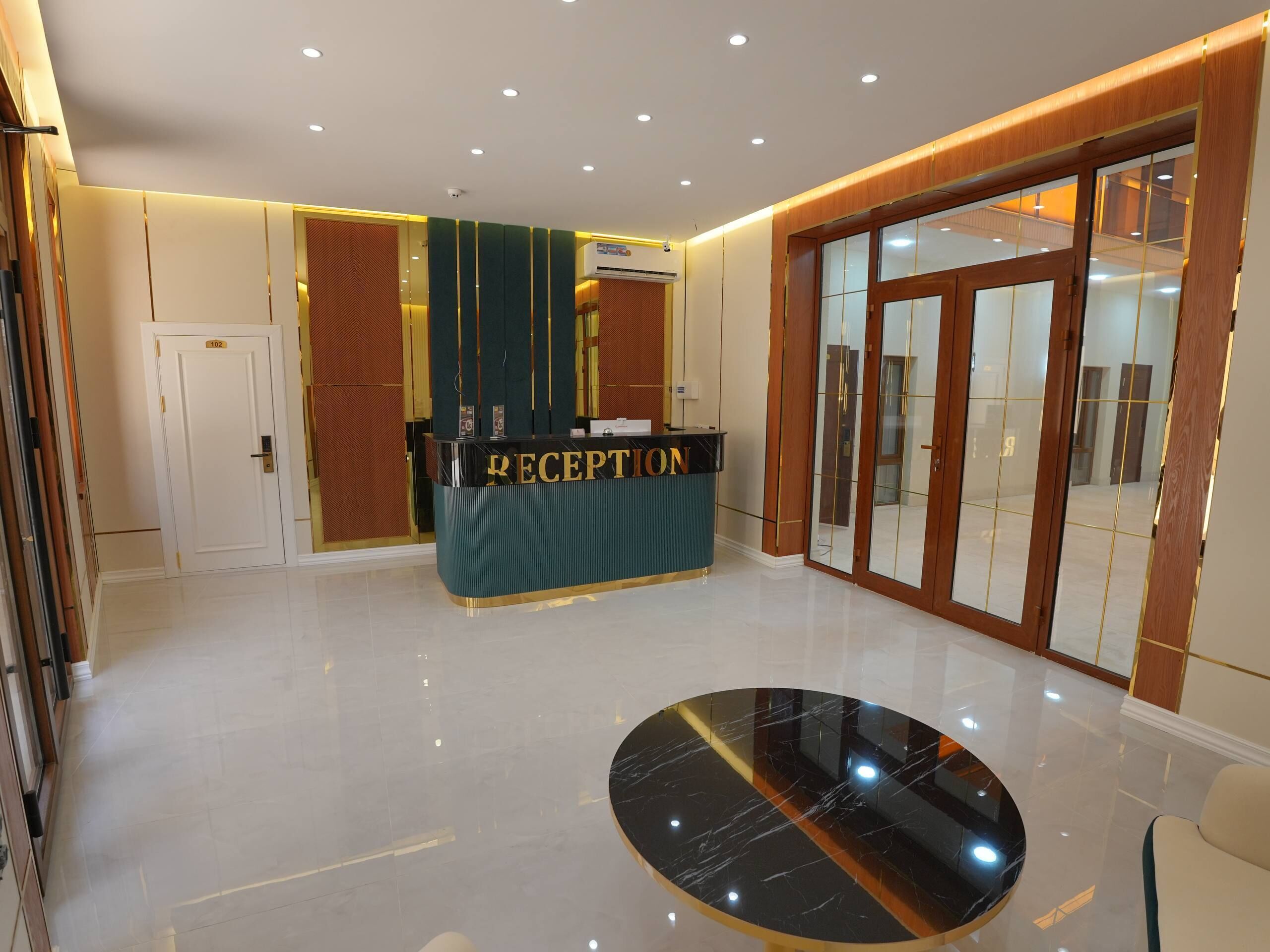 A reception area with a reception desk, a glass door entrance, and a polished floor.