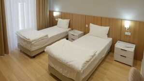 A hotel room with two beds, a desk, and a chair. - Darvaza Boutique Hotel (Bukhara)