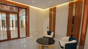 A modern lobby with a glass door entrance, a round table with chairs, and a wooden accent wall. - Darvaza Boutique Hotel (Bukhara)