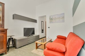 Ein modernes Wohnzimmer mit einem grauen Sofa, einem Fernseher und einem Gemälde an der Wand.