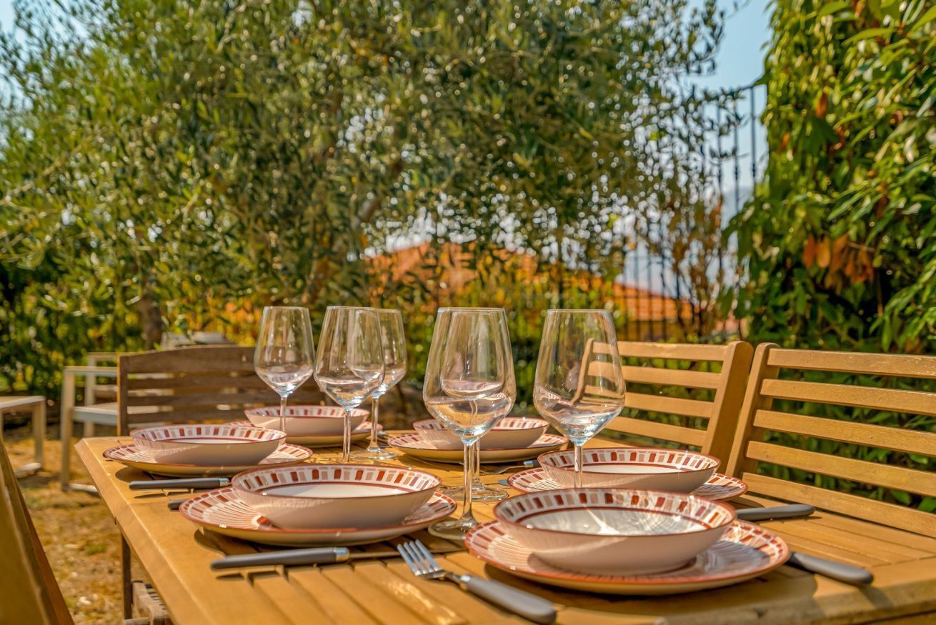 Een tafel buiten gedekt met borden, glazen en bestek.