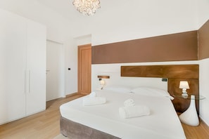 A modern hotel room with a large bed, bedside lamps, a wardrobe, and a wooden headboard. - [Val Zagora] 5Terre-Private parking (La Spezia)