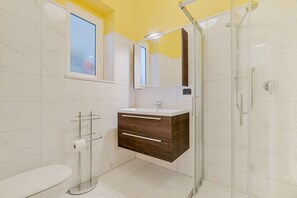 Ein Badezimmer mit Toilette, einem Waschbecken mit Spiegel und einer Duschkabine.