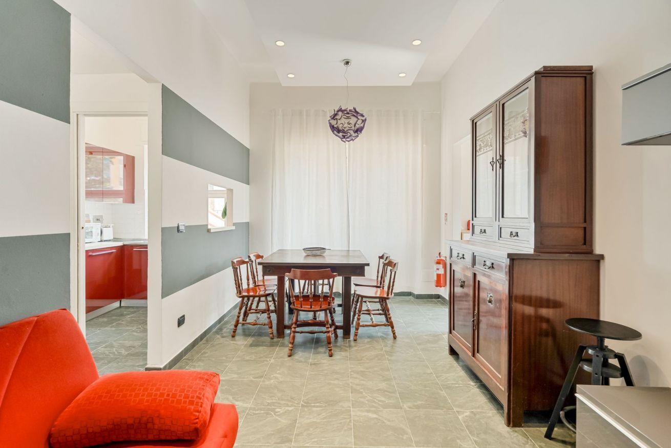 A modern kitchen with a dining table, chairs, and a cabinet.
