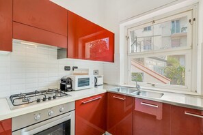 Eine Küche mit Gasherd, Mikrowelle und einem Fenster mit Blick auf Gebäude.