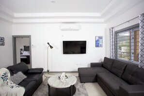 Ein modernes Wohnzimmer mit einem Flachbildfernseher, zwei Sofas, einem Couchtisch und einer Stehlampe.