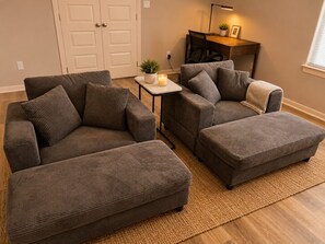A living room with two grey sofas, a small table with a candle, and a desk with a lamp. - Luxury 3BR - Office -  Pool -  Fast WiFi (MCALLEN)