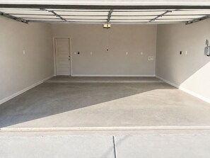 A garage with a concrete floor, a door, and a ceiling with visible ductwork. - Luxury 3BR - Office -  Pool -  Fast WiFi (MCALLEN)
