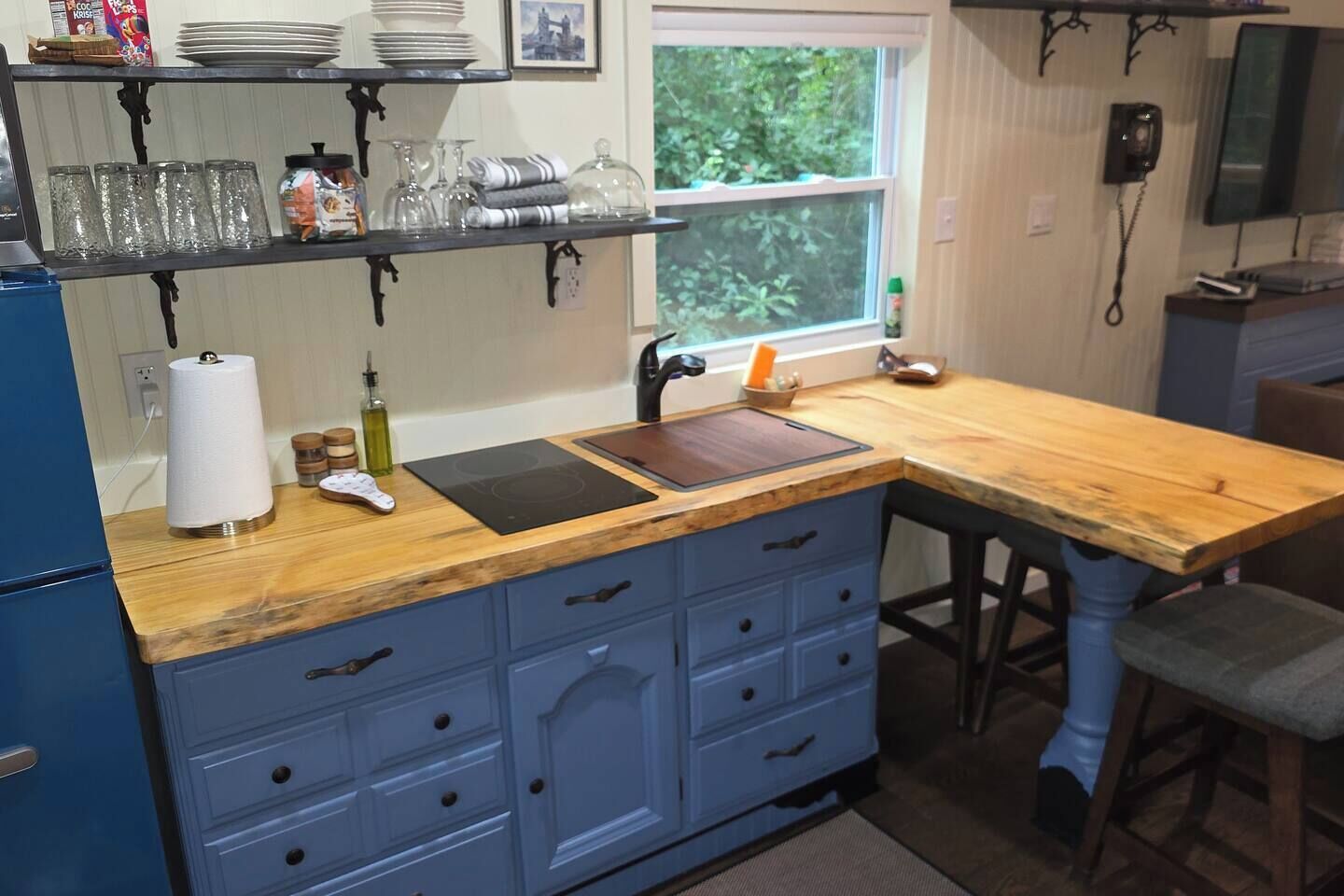 Une cuisine avec un plan de travail en bois, un évier et un meuble bleu avec des tiroirs.