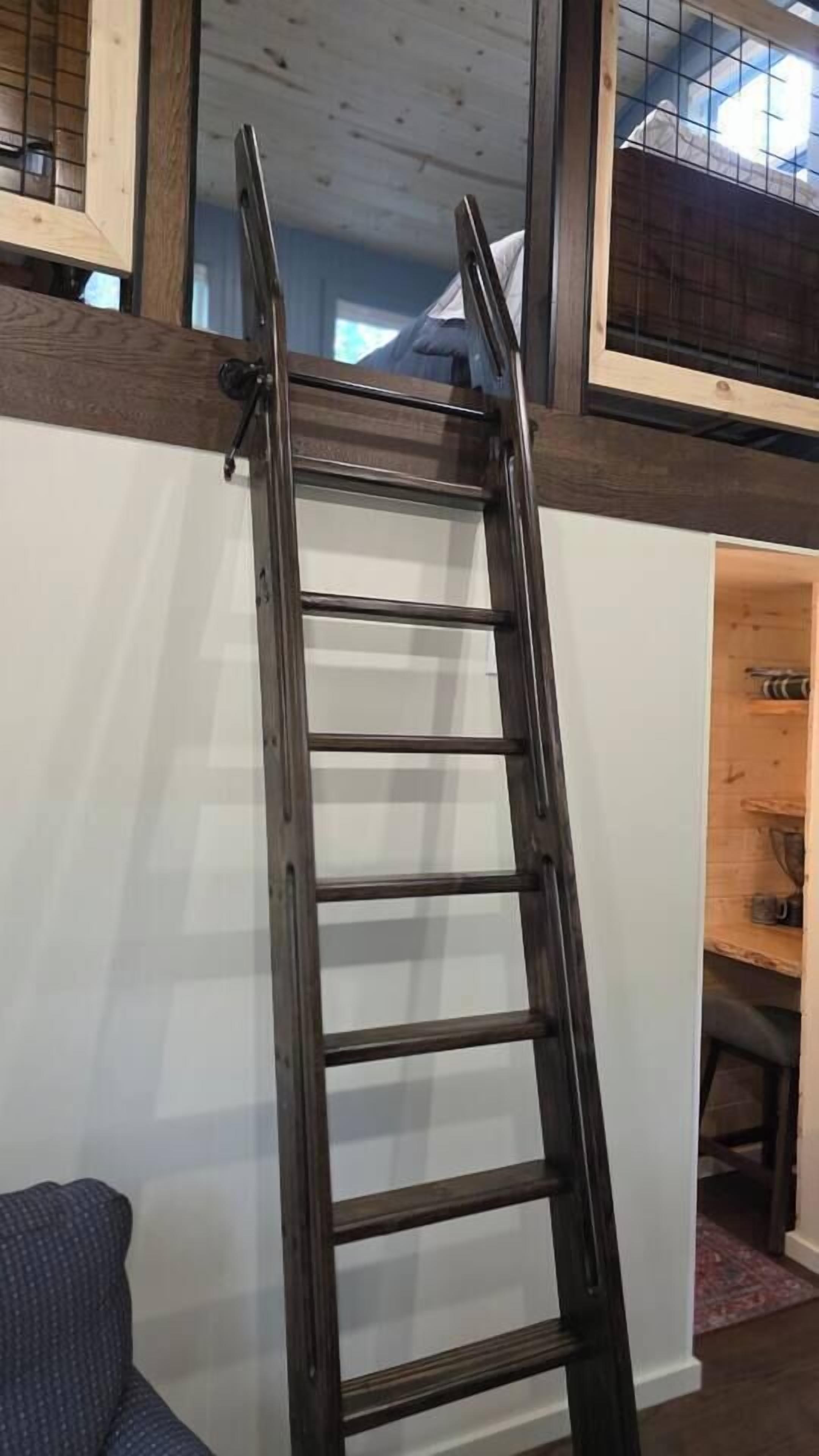 A wooden ladder against a white wall with a window above it.