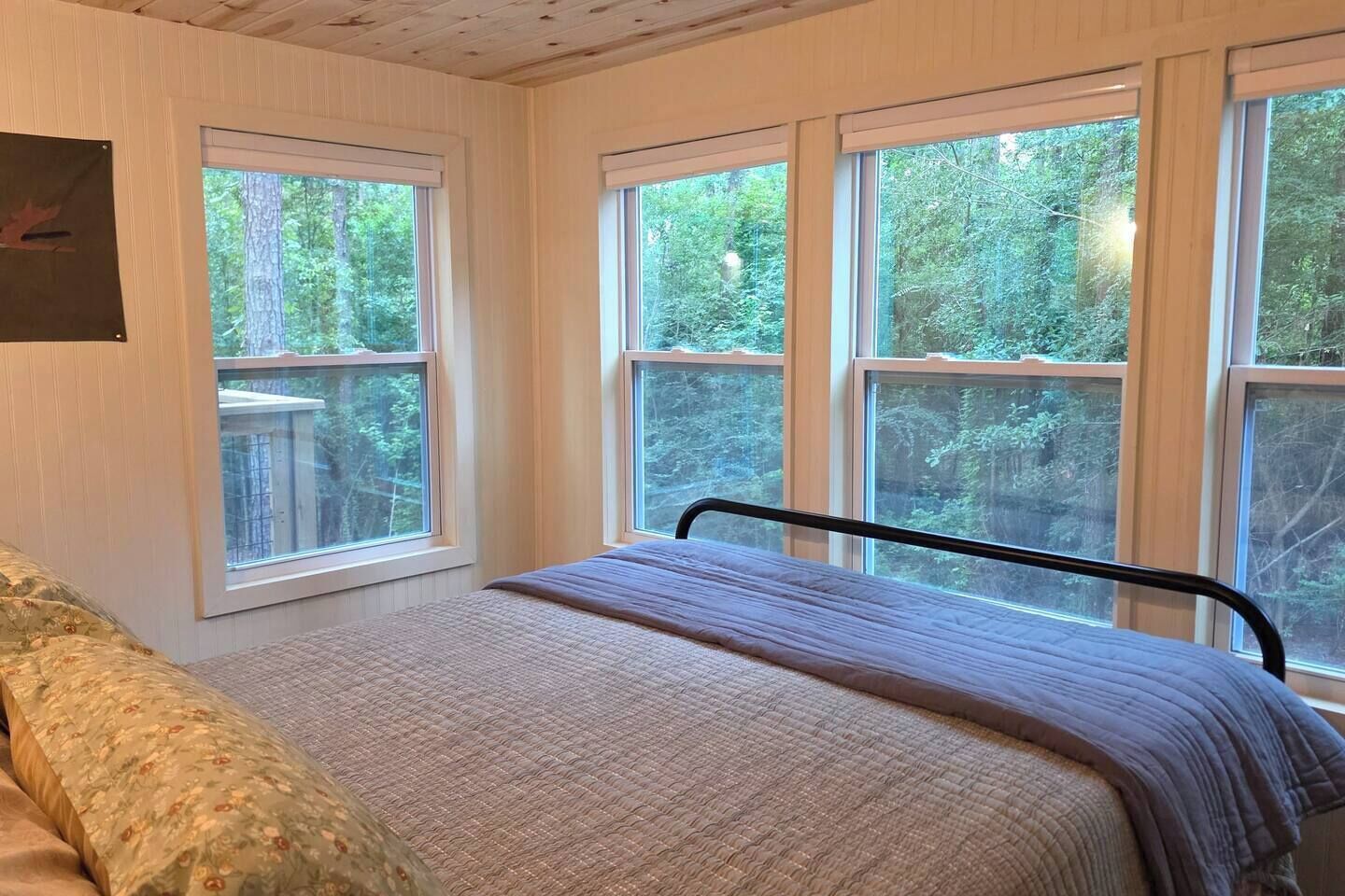 Una camera da letto con un letto, una finestra e vista su alberi.