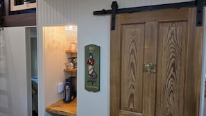 A wooden door with a plaque, a coffee machine, and a shelf with a mug and a kettle.