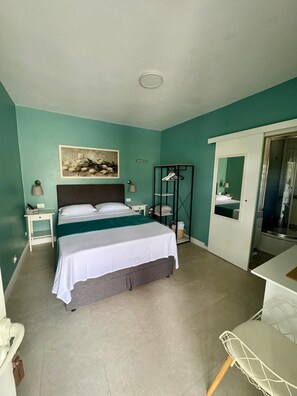 A bedroom with a bed, a nightstand, a dresser, a mirror, and a door leading to a bathroom.