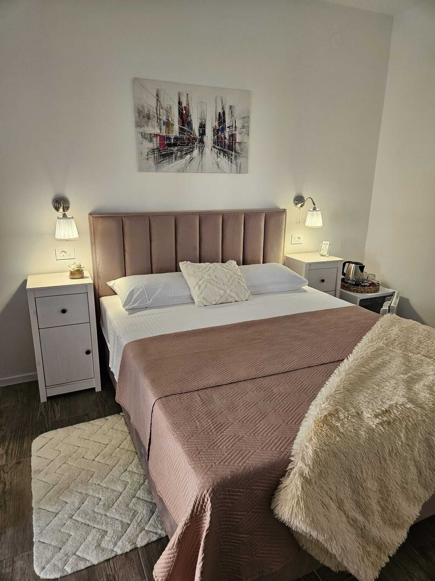 A hotel room with a large bed, two bedside tables, a nightstand, a decorative wall piece, and a rug.