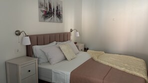 A bedroom with a bed, bedside tables, a nightstand, a lamp, and a painting on the wall.