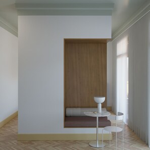 Un interior modern amb una zona d'seure integrada, una taula rodona amb un bol blanc i una petita taula auxiliar.