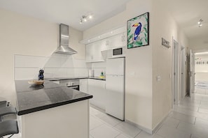 A modern kitchen with white cabinetry, a black countertop, and a built-in microwave. - Vacation Apartment 'Vacanze Mareverde' with Mountain View, Shared Pool and Wi-Fi (Costa Adeje)